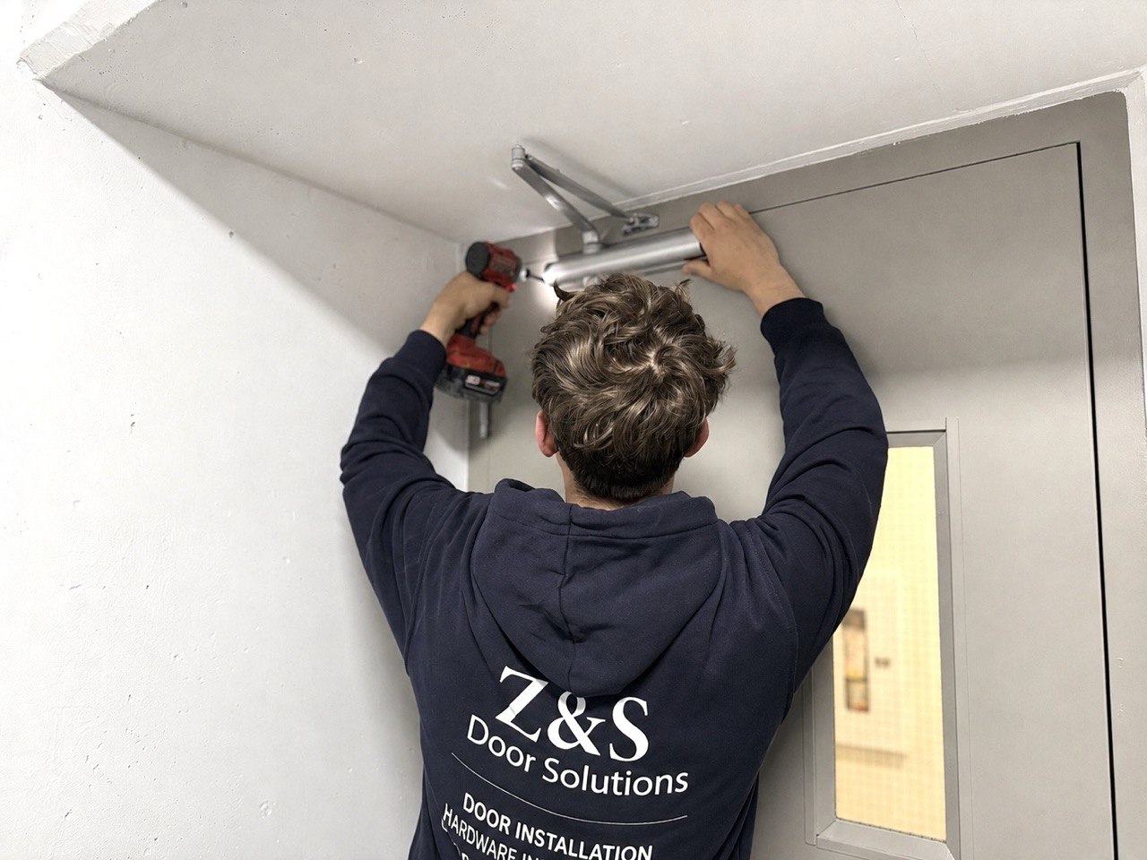 Z&S Door Solutions technician installing a door closer